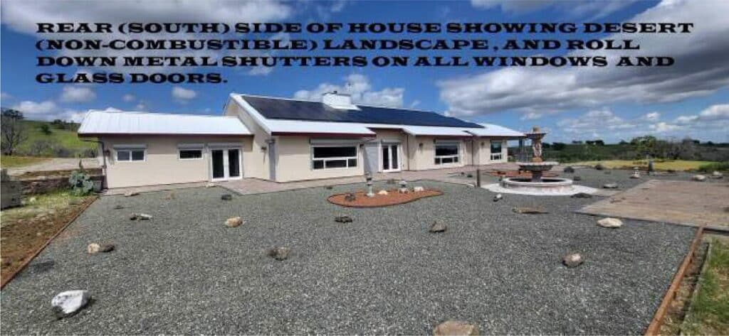 Rear (South) side of house showing desert (non-combustible) landscape, and roll down metal shutters on all windows and glass doors
