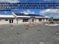 Rear (South) side of house showing desert (non-combustible) landscape, and roll down metal shutters on all windows and glass doors
