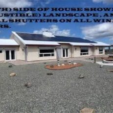 final house Rear (South) side of house showing desert (non-combustible) landscape, and roll down metal shutters on all windows and glass doors